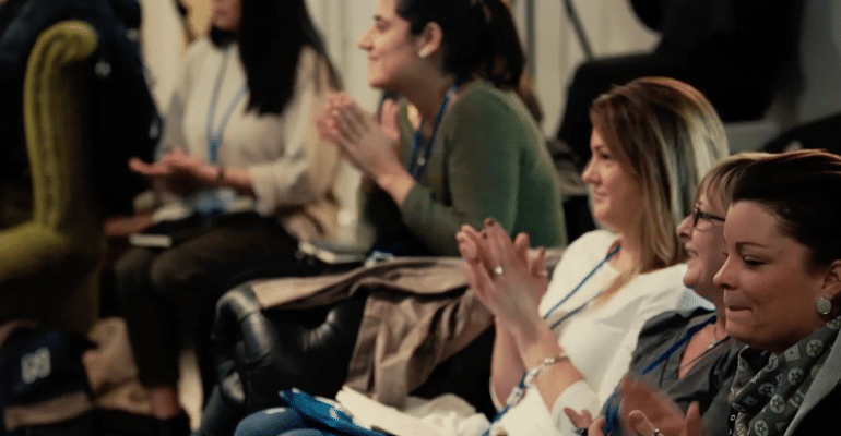 Seated audience clapping and taking notes in presentation